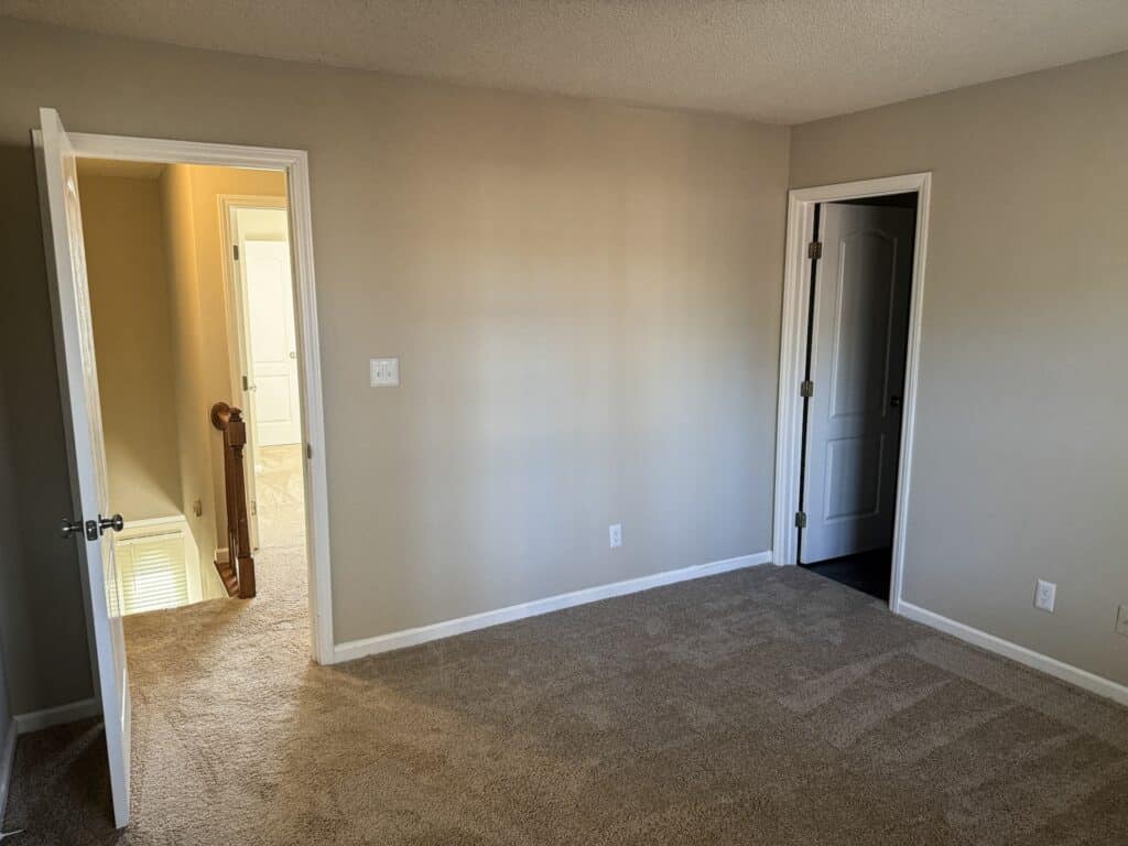 Unfurnished room with beige carpet, light gray walls, an open door leading to a hallway, and another closed door on the right.